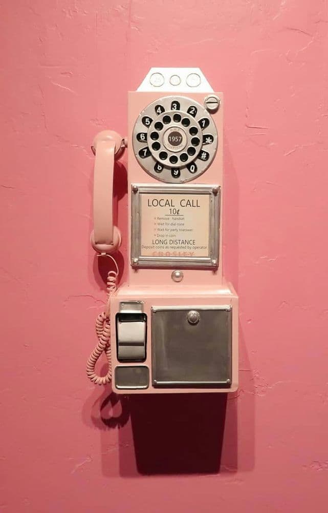 gammal telefon på rosa vägg